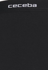 Black cotton shirt featuring a ribbed texture, with white "ceceba" logo stitched at the neckline. Simple design, no additional patterns or accents.