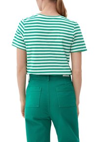 Zelené a bílé pruhované tričko s krátkým rukávem, vyrobené z bavlny. V kombinaci s vysokými zelenými kalhotami s dvěma zadními kapsami.