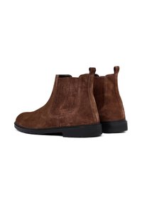 Stivali alla caviglia in suede marrone con pannelli elasticizzati sui lati e linguette di estrazione, dotati di suola in gomma nera e texture liscia.