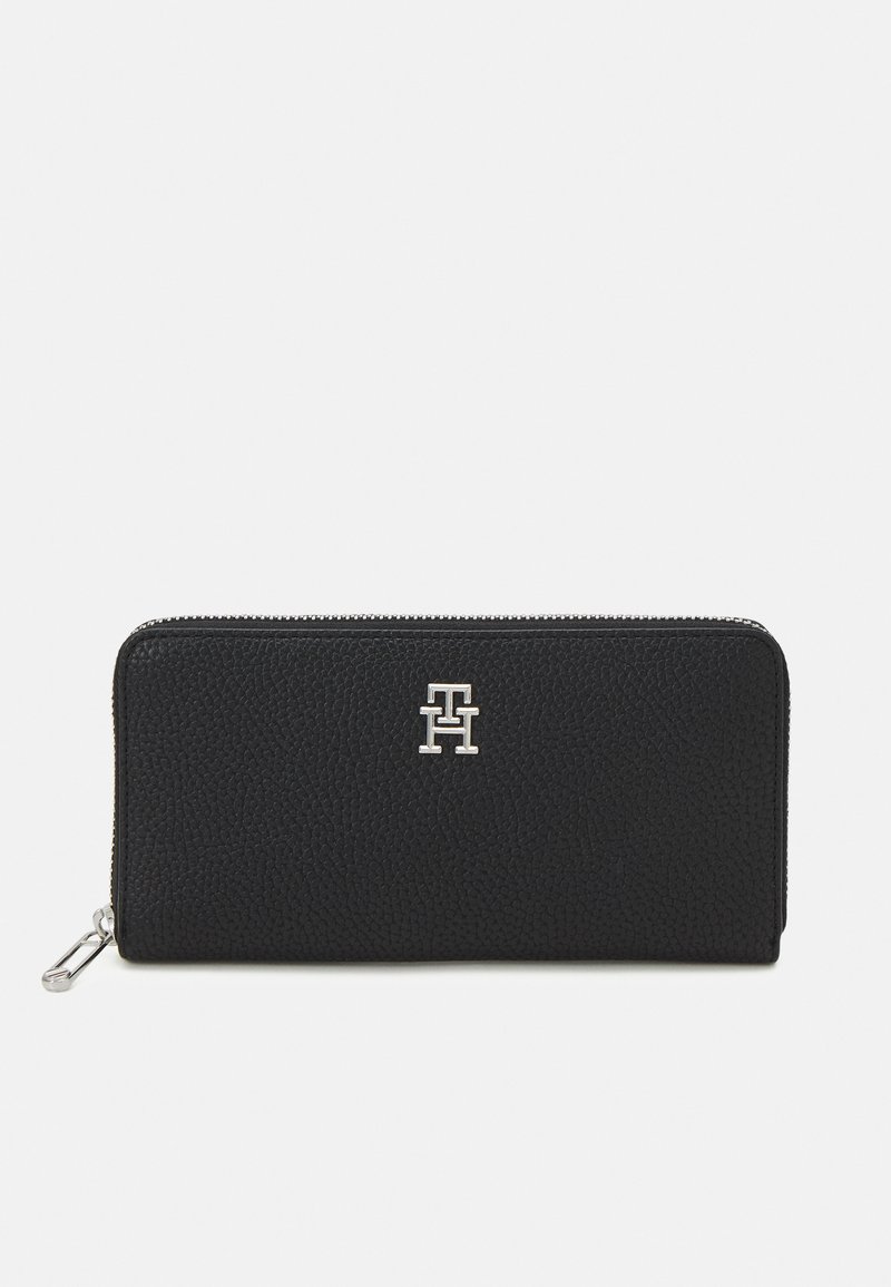 Black leather wallet with a textured finish, zip closure, and silver logo accent on the front. Compact rectangular shape, minimal design.