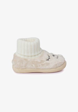 Fuzzy beige slipper with a ribbed white ankle cuff, featuring a stitched face design and a textured rubber sole for grip.