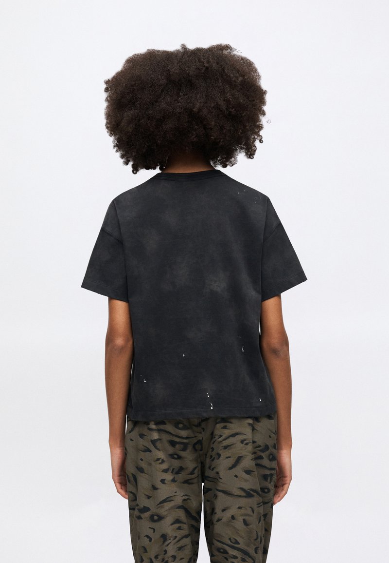 Sort t-shirt med korte ærmer, der har en falmet tekstur med let slid. T-shirten har rund halsudskæring og afslappet pasform.