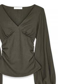 Tamsiai alyvuogių žalios spalvos marškiniai su tekstūruota medžiaga. Yra V formos iškirptė, susiraukšlėtos detalės krūtinėje ir juosmens srityje, o taip pat ilgomis, plačiomis rankovėmis.