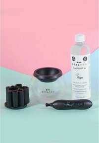 Makeupborststvättsats inklusive en klar glasbowl med svart kant, en flaska vegansk rengöring, en svart elektrisk snurrmaskin och silikonhållare.