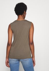 Top senza maniche verde oliva con scollatura rotonda, realizzato in tessuto morbido, con una forma aderente e orlo dritto sul bordo inferiore.
