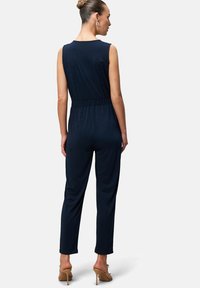 Navy blue jumpsuit with a sleeveless design, elastic waistband, and straight legs. Soft, smooth fabric with a fitted silhouette.