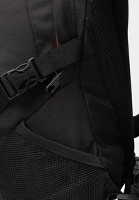 Zaino in tessuto nero con superficie testurizzata, fibbia regolabile, dettagli in tasca a rete e design elegante.