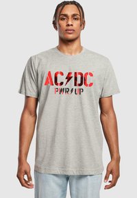 Graues Baumwoll-T-Shirt mit rotem AC/DC-Text und Blitzgrafik. Kurze Ärmel und Rundhalsausschnitt. Schlichte, lässige Passform.
