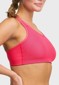 Roze sportbeha met een naadloos ontwerp, brede schouderbanden en een gestructureerde stof voor extra ondersteuning en flexibiliteit.