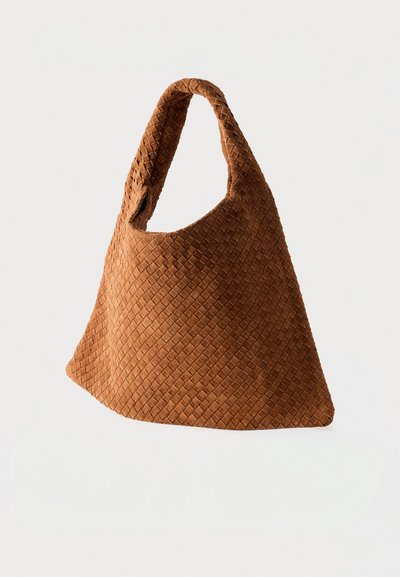 Καφέ πλεκτή δερμάτινη τσάντα tote με χαλαρή, τριγωνική μορφή και φαρδιά ράβδο, τοποθετημένη πάνω σε απλό λευκό φόντο.