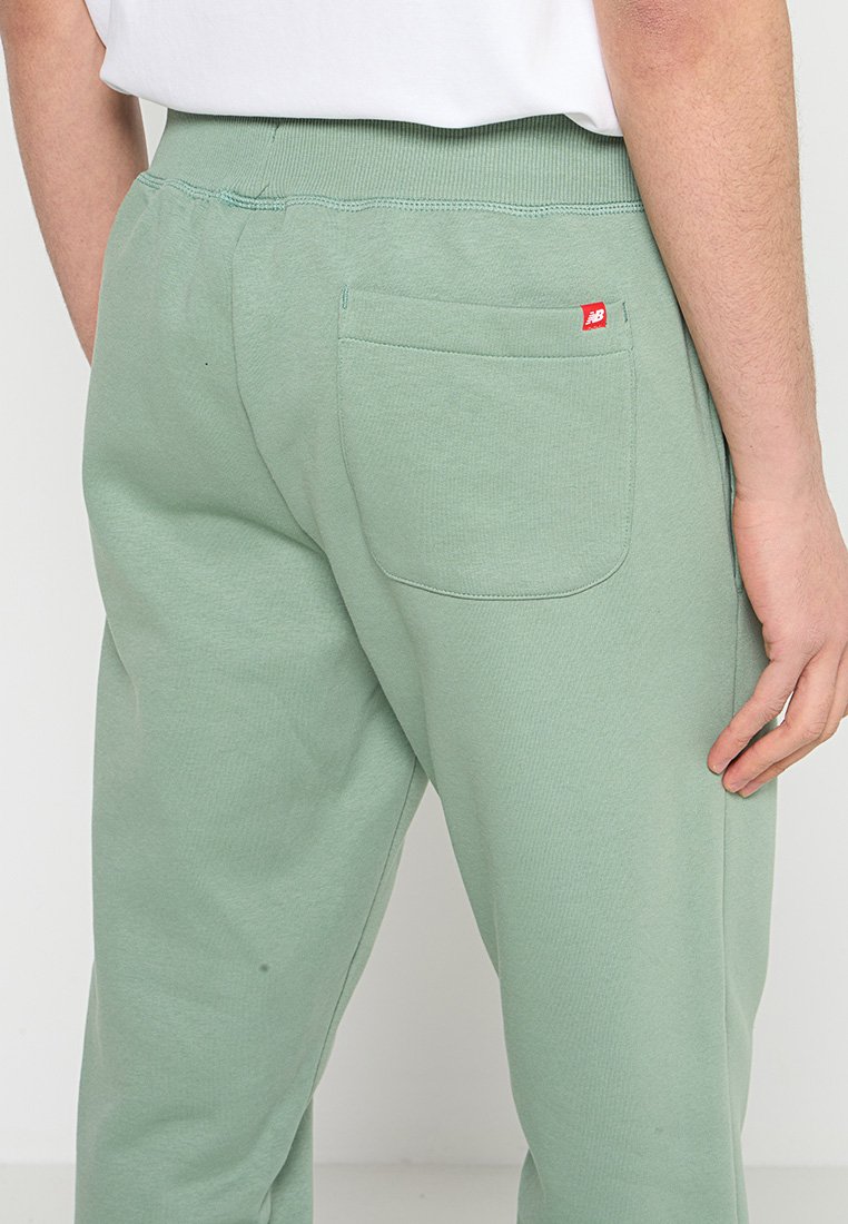 Hellgrüne Baumwoll-Sweatpants mit einem elastischen Bund, einer einzelnen Gesäßtasche und einem kleinen roten Logoakzent in der Nähe der Tasche.