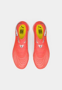 Jasnoróżowe buty sportowe z siateczkową cholewką, fakturą w kropki, odblaskowymi akcentami i amortyzowaną żółtą wkładką.