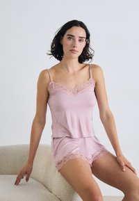 Soft pink tank top and shorts set, featuring lace accents along the neckline and hem. Made of lightweight, smooth fabric.