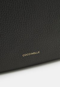 Borsa in pelle nera con superficie testurizzata, dettagli del logo dorato. Il design è rettangolare con linee pulite e accenti sottili.