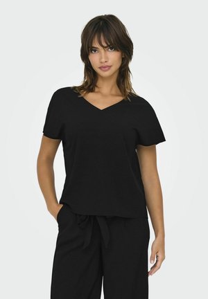 Sort V-hals t-shirt i blødt stof, kortærmet, afslappet pasform, parret med løse sorte bukser. Enkel design, ingen mønstre eller accenter.