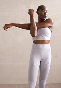 Lichtgrijze sportieve crop top en leggings, met een gladde textuur, geperforeerde details en een aansluitend ontwerp, geschikt voor oefeningen.