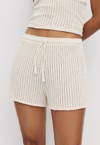 Lichtcrème geribde shorts gemaakt van zachte gebreide stof, voorzien van een tailleband met trekkoord en een geschulpte zoomafwerking.