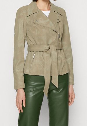 Veste de moto en simili cuir beige clair avec une taille ceinturée, des poches zippées et des détails en relief sur les manches.