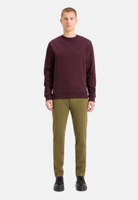 Bordeaux sweatshirt med rund hals og ribbede manchetter, parret med olivengrønne bukser og sorte snørebåndssko. Enkel, strømlinet design.