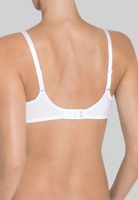 Vitt bh med justerbara band, hak- och ögontapp, slät textur och minimalistisk design, sedd bakifrån.