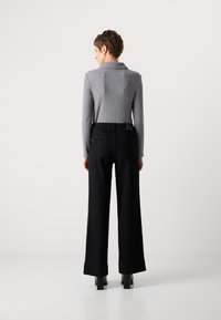 Top gris de manga larga acanalada combinado con pantalones de pierna ancha negros de talle alto, que presentan una textura suave y un diseño trasero minimalista.