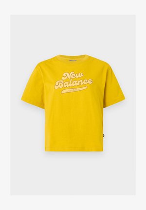 Sárga, rövid ujjú pamut póló, amelyen egy nagy, világos színű "New Balance" logó található, ívelt aláhúzással.