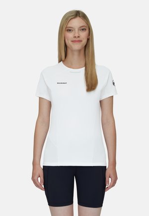 Vit kortärmad träningsskjorta med rund halsringning, med logotypdetaljer. Materialet verkar jämnt och ventilerande, matchat med mörka shorts.