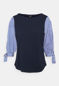 Mörkblå blus med blå och vita vertikala randiga 3/4-ballongärmar knutna vid ärmsluten, rund halsringning.