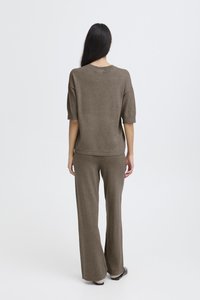 Brown knit top with short sleeves paired with loose-fitting brown knit pants. Soft texture, simple design, and matching color scheme.