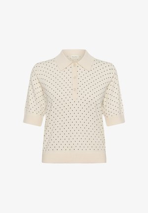 Polo a maniche corte color crema con piccoli pois neri, tre bottoni frontali, maniche con polsini e orlo a coste.