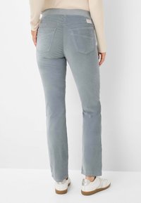 Lichtgrijze, slimfit corduroy broek met een middelhoog figuur, achterzakken en een subtiele textuur, gecombineerd met witte sneakers.