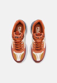 Orange und weiße Sportschuhe mit Netzdetails, dicke Sohle und mehrfarbigen Akzenten. Mit auffälliger Markenkennzeichnung auf Zungen und Seiten.