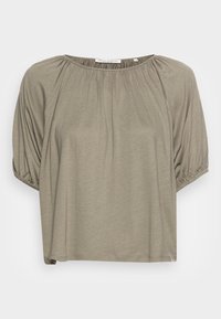 Top grigio a maniche corte con scollatura rotonda, caratterizzato da dettagli in tessuto arricciato lungo le spalle e una vestibilità rilassata. Tessuto morbido e liscio.