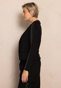 Schwarzer, maßgeschneiderter Blazer mit grau gestreiften Akzenten an den Ärmeln, zwei Vordertaschen und einem Ein-Knopf-Verschluss. Glatte Stofftextur.