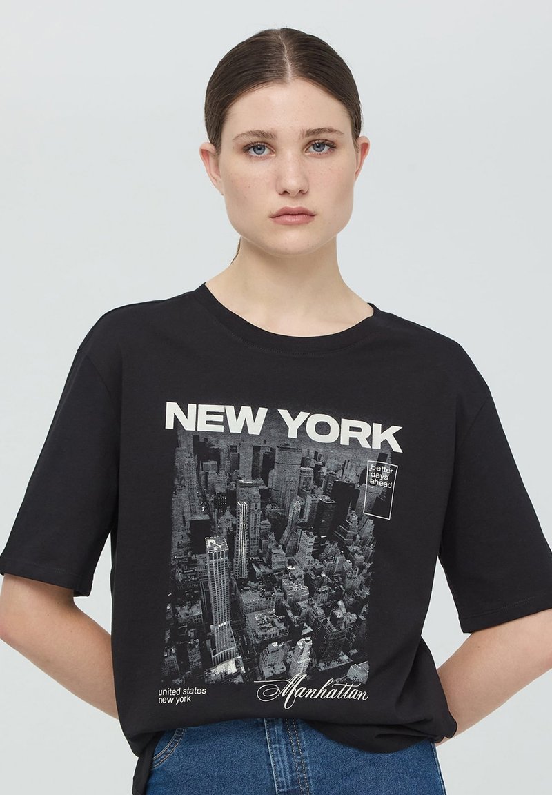 Maglietta nera a maniche corte con stampa grafica di Manhattan, con il testo "NEW YORK" e "giorni migliori in arrivo" in bianco.
