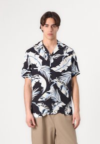 Camicia a maniche corte con bottoni in tessuto nero, caratterizzata da grandi motivi di foglie di palma bianche e blu, con colletto piatto e vestibilità rilassata.
