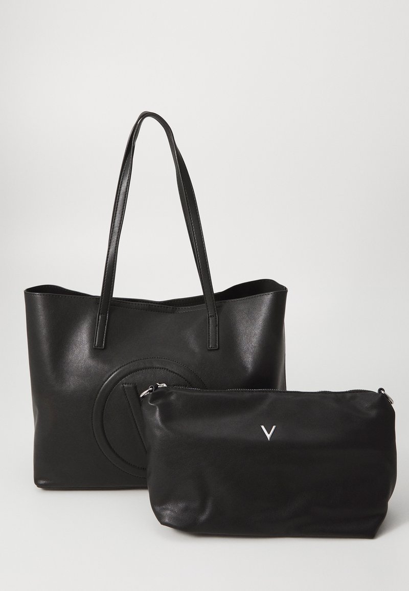 Svart läderhandväska med långa handtag, med en cirkulär präglad design. Inkluderar en mindre svart väska med dragkedja och en silverfärgad logotyp.