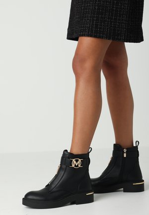 Botas negras hasta el tobillo hechas de cuero texturizado, con un acento de logo dorado, detalle de cremallera y un tacón bajo en bloque.