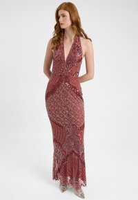 Abito rosso con scollo all'americana, decorato con intricate lavorazioni di perline, dotato di un profondo scollo a V e una silhouette aderente che si allarga all'orlo.