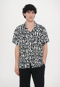 Κοντομάνικο πουκάμισο από μαύρο ύφασμα με λευκό λουλουδένιο και αφηρημένο σχέδιο, με ντεκολτέ και χαλαρή εφαρμογή.