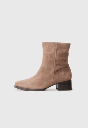 Bottine en daim de couleur brun clair avec un bout rond et un talon bloc de hauteur intermédiaire. Caractéristiques d'une texture lisse et d'un design simple.