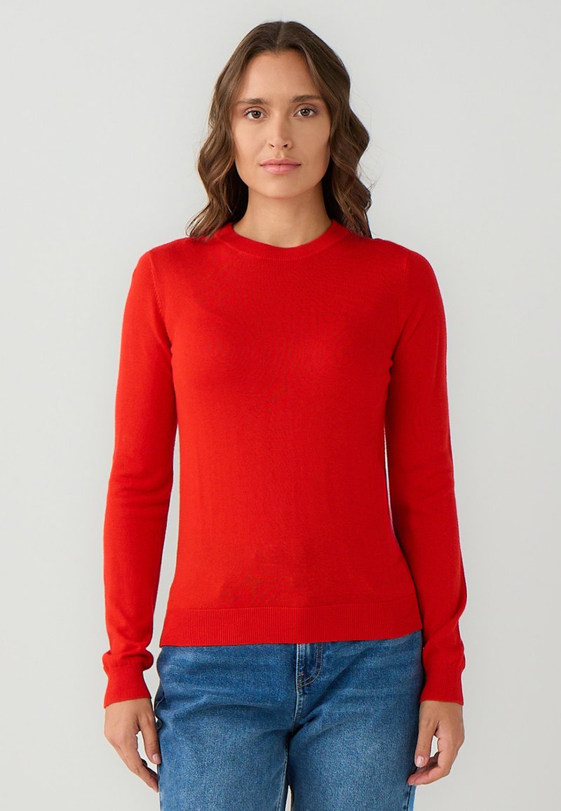Pull rouge à manches longues avec un col rond, présentant un design ajusté et des poignets et un ourlet côtelés ; texture lisse et tissu léger.