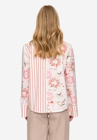 Camicia a maniche lunghe con stampe miste di strisce rosse e disegni di sole in rosa e oro. Realizzata in tessuto leggero con una texture liscia.