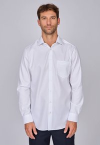 Chemise blanche à manches longues avec boutons, en tissu lisse, dotée d'une poche avant et d'un col classique. Légère brillance, coupe ajustée.