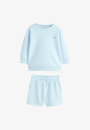 Sweatshirt pour enfants à manches longues bleu clair avec un petit visage souriant sur la poitrine et short à cordon assorti.