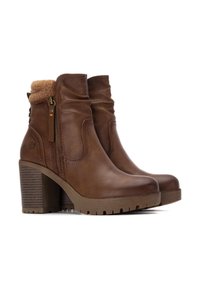 Botas de tobillo de cuero marrón con un tacón texturizado y grueso, forro de piel sintética y detalle de cremallera lateral para una fácil colocación.