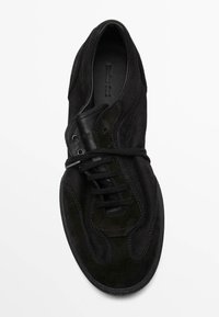 Sneaker in suede nero con punta rotonda, linguetta imbottita e cuciture a contrasto. Presenta lacci piatti e suola in gomma testurizzata.