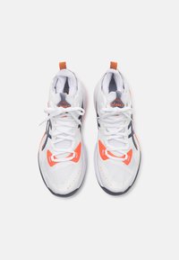 Witte sportschoenen met oranje en grijze accenten, een bovenwerk van mesh, platte veters en een uitgesproken demping op de zool.