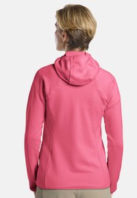 Sweat à capuche rose avec une finition texturée, doté d'une fermeture éclair à l'avant et d'une capuche ajustée, adapté pour une utilisation active.