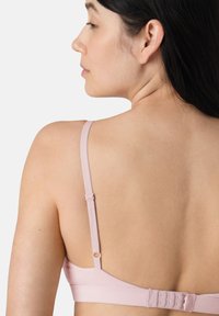 Reggiseno rosa chiaro in tessuto morbido, con spalline regolabili e molteplici chiusure a gancio e occhiello sul retro per regolare la vestibilità. Texture liscia.